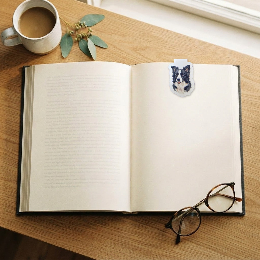 Border Collie watercolor magnetic bookmark on an open book on a wooden desk with coffee and reading glasses