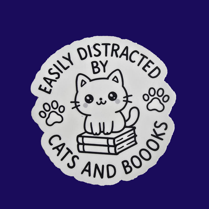 "Die-cut vinyl sticker with a black-and-white kawaii cat sitting on books, surrounded by the text &
