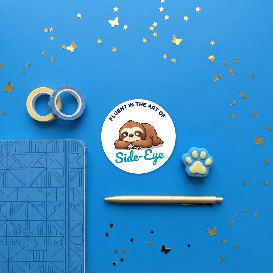 Fluent in the Art of Side-Eye sticker in a blue flat lay with washi tape and a pen