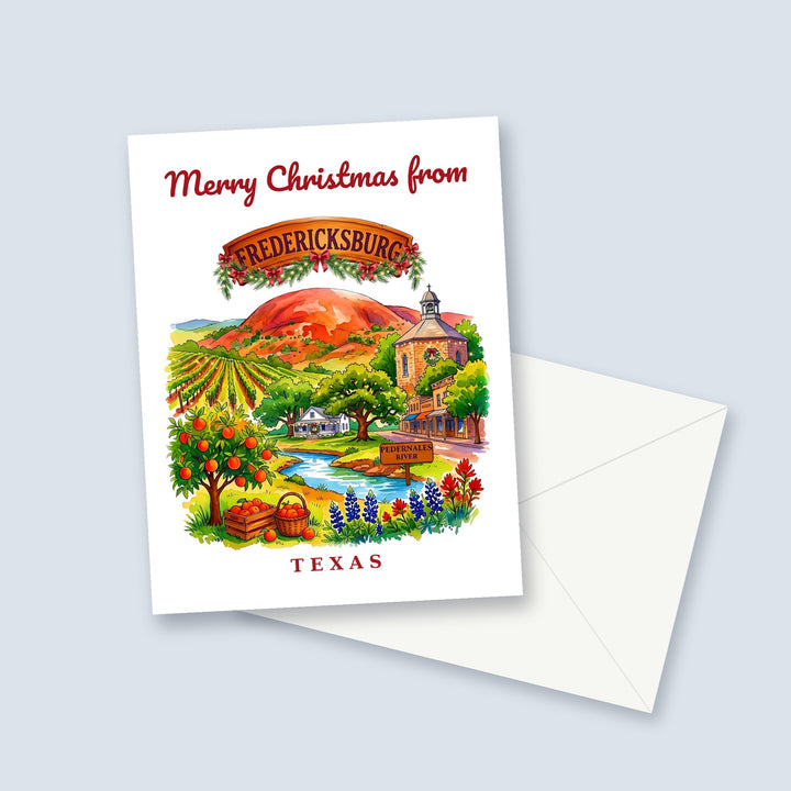 Merry Christmas from Fredericksburg Texas watercolor Christmas card with Enchanted Rock, vineyards and bluebonnets, a garland-trimmed town sign and a white envelope