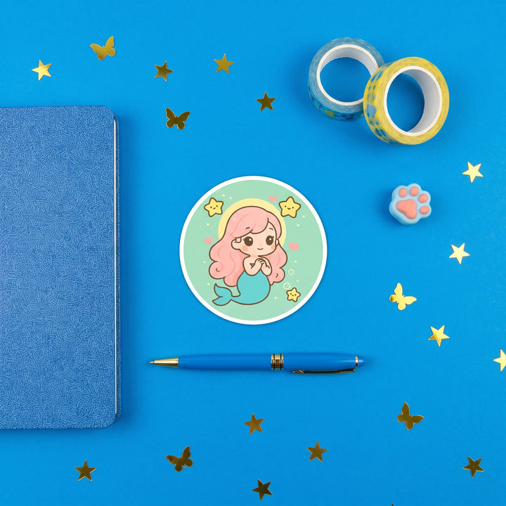 Kawaii Pink Mermaid Sticker in a blue flat lay