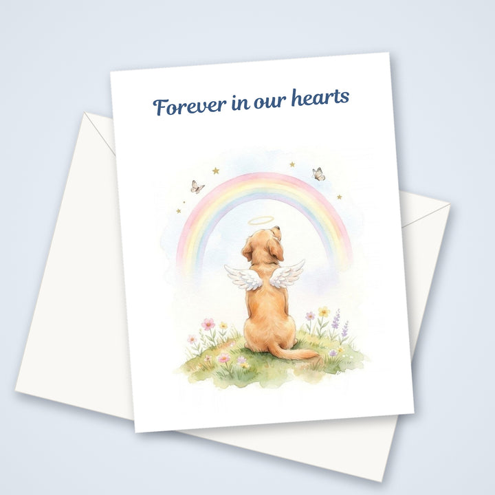 Pet sympathy greeting card for dog loss with a watercolor angel dog looking at a rainbow and the words Forever in our hearts, shown with a white envelope