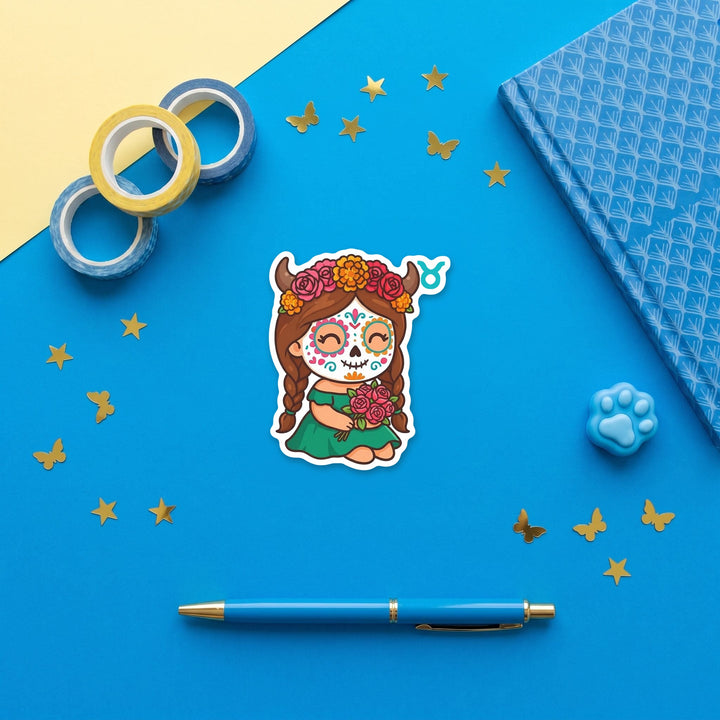Taurus sugar skull girl 3 inch sticker flat lay with blue and yellow stationery – Designs by Mysh