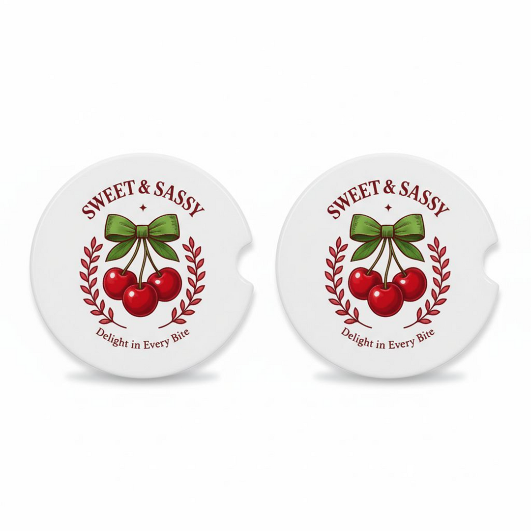 Set of two ceramic car coasters with a retro cherry design, green bow, and the phrases “Sweet & Sassy” and “Delight in Every Bite,” printed on a white background.