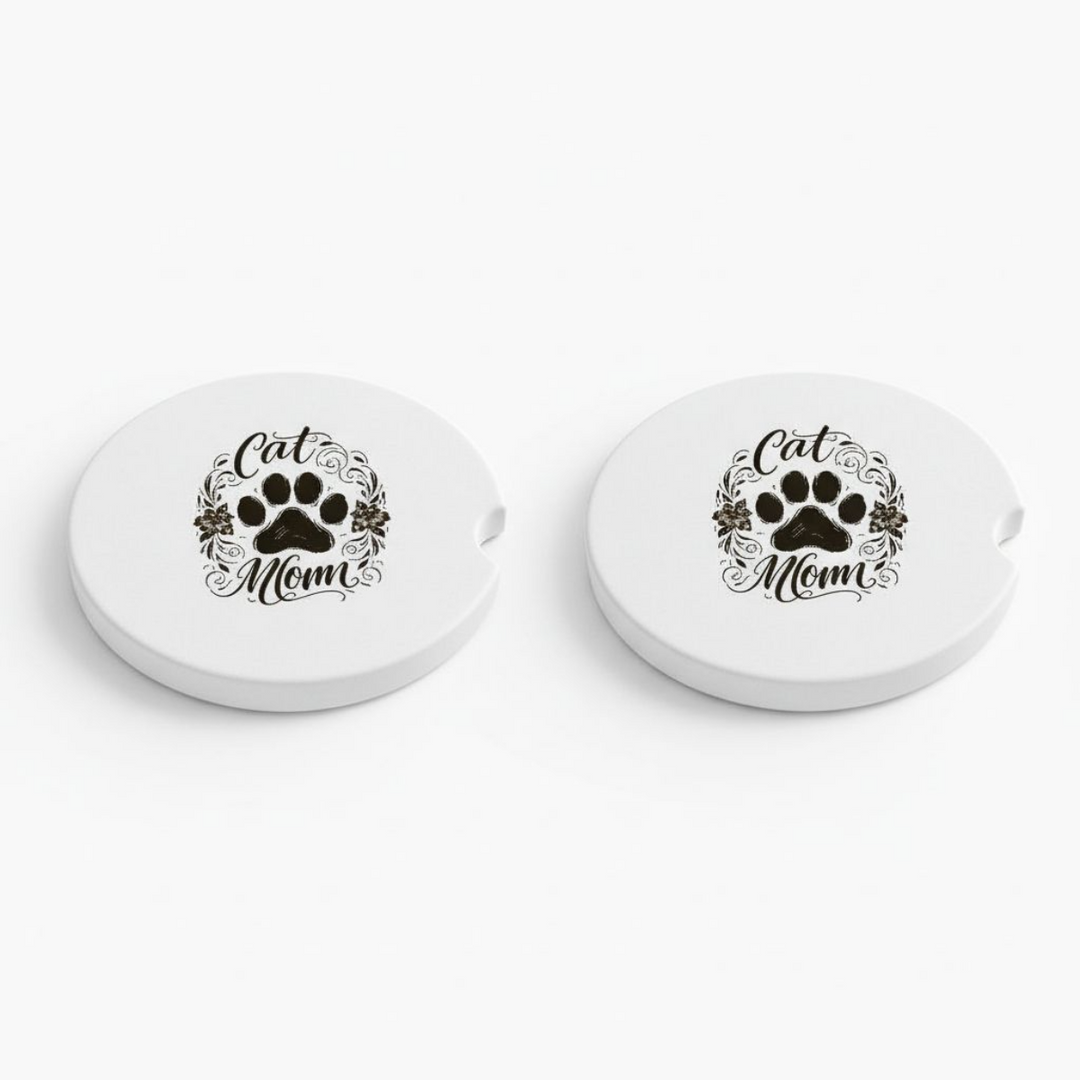 Set of two white ceramic car coasters featuring a black paw print with floral scrolls and the words "Cat Mom" in elegant script, with a side notch for easy removal.