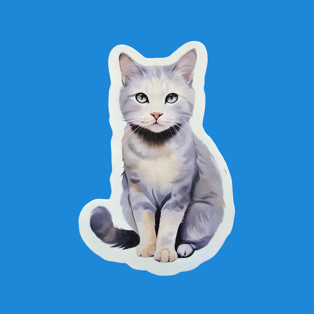 A die-cut sticker of a gray and white cat with green eyes, shown against a solid blue background.