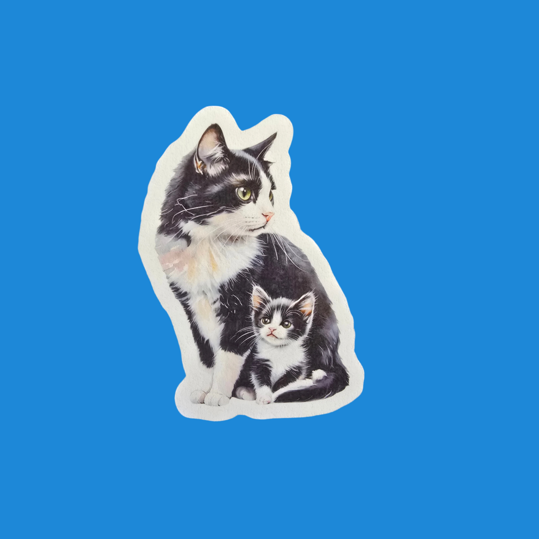 A die-cut sticker featuring a black and white tuxedo cat sitting next to a smaller kitten, shown on a solid blue background.