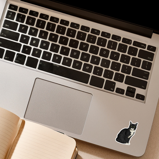 Laptop with a cat-shaped sticker on the palm rest area, placed on a light surface.