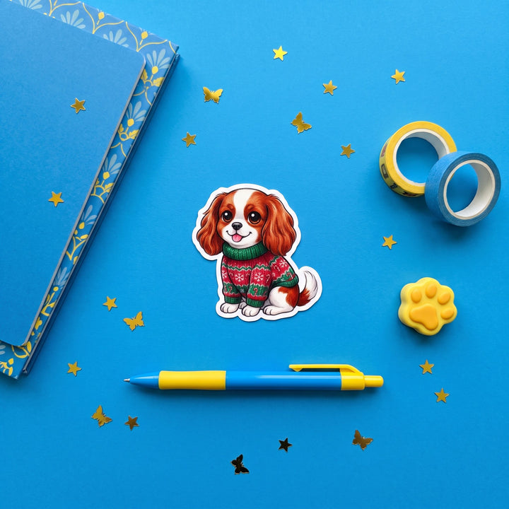 Blenheim Cavalier King Charles ugly Christmas sweater 3 inch sticker flat lay with blue and yellow stationery – Designs by Mysh