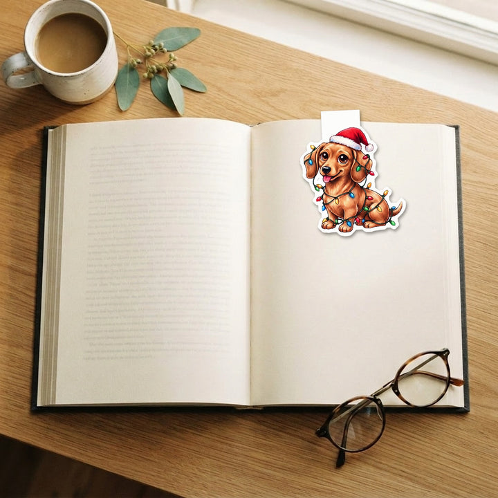 Red Dachshund in Santa hat tangled in Christmas lights kawaii magnetic bookmark clipped on an open book – Designs by Mysh