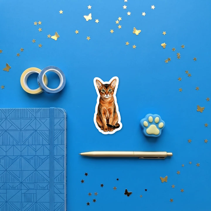 Abyssinian Ruddy watercolor 3 inch sticker flat lay with blue and yellow stationery – Designs by Mysh