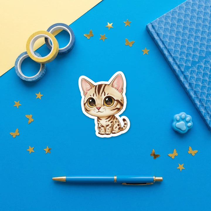 Ocicat Chocolate Spotted kawaii 3 inch sticker flat lay with blue and yellow stationery – Designs by Mysh