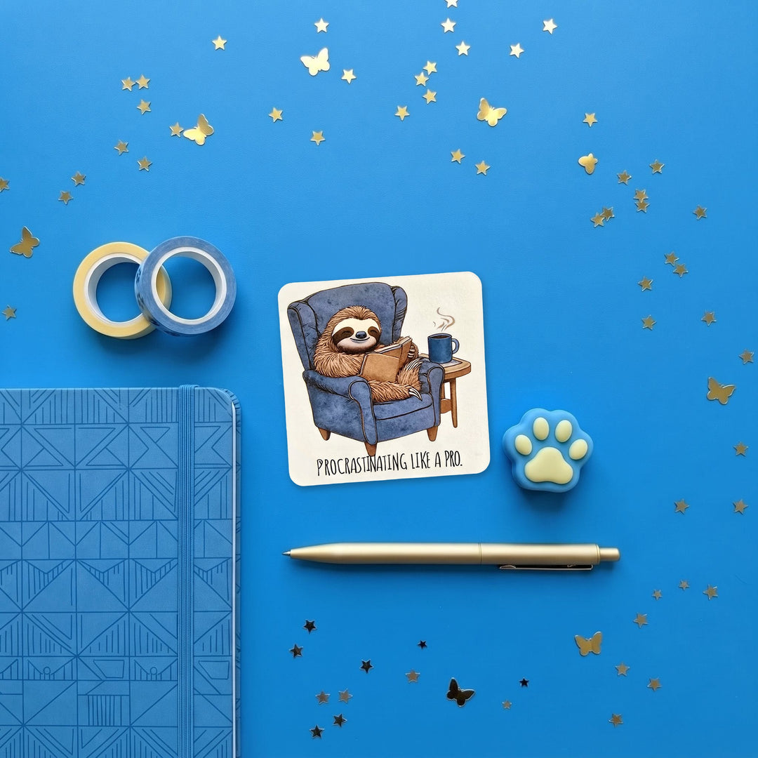 Procrastinating Like a Pro sloth sticker in a blue stationery flat lay