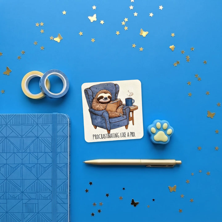 Procrastinating Like a Pro sloth sticker in a blue stationery flat lay
